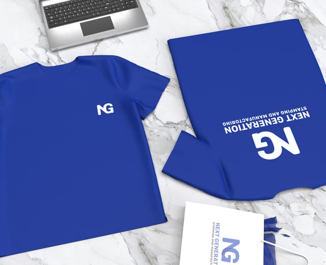 A flat lay of navy branded apparel and a notebook carrying the NG monogram, shot on white marble beside a keyboard.